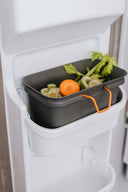 Grey food scrap bin sitting in freezer door